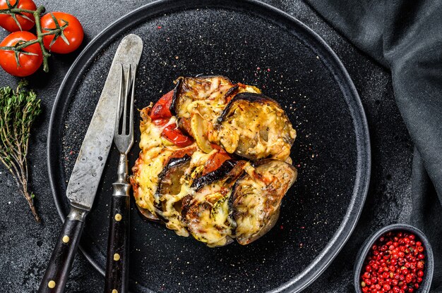 Vegetable ratatouille on a plate. French Provencal casserole. Black background. Top view.