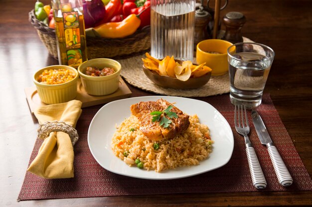 Vegetable rice with pork chop Peru peruvian comfort food serving on wooden table