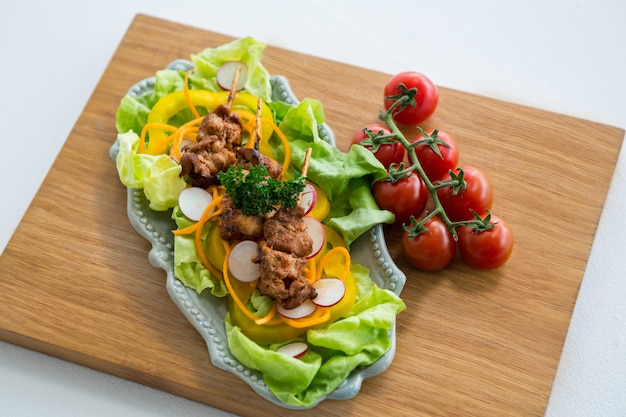 Vegetable salad and cherry tomato on wooden board