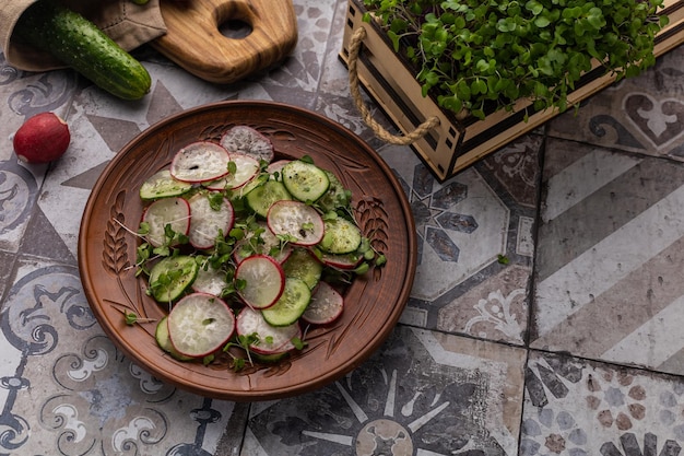 Овощной салат из свежей редьки и огурца с микрозеленью на кухонной тарелке