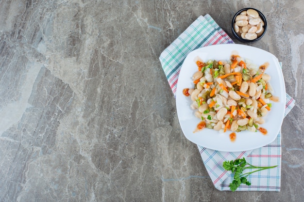 Vegetable salad on plate on a tea towel , on the marble background.