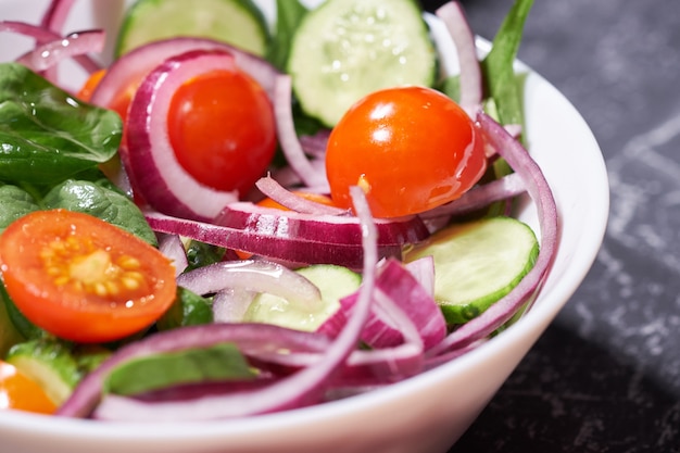 Vegetable salad in a white plate on a gray background