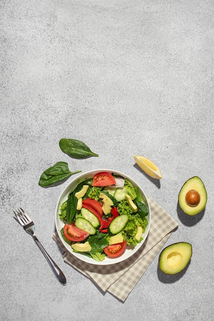 Insalata di verdure con avocado in un piatto bianco su sfondo grigio