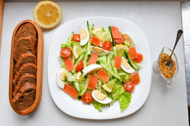 Vegetable salad with bread and mustard. on a white plate. view from above