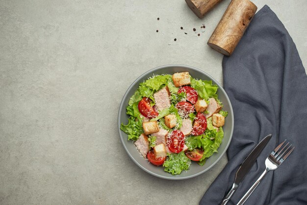 Vegetable salad with chicken and cheese on a gray table Caesar salad in a gray plate