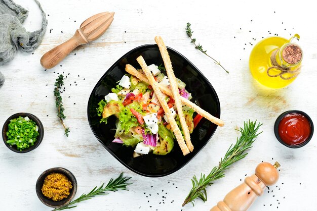 Vegetable salad with chicken zucchini and feta cheese on a black plate Top view Free space for your text