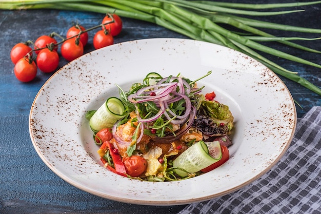 Vegetable salad with fresh cucumbers, marinated tomatoes, lettuce, arugula and onion.