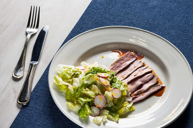 Vegetable salad with meat and sauce on a large white plate