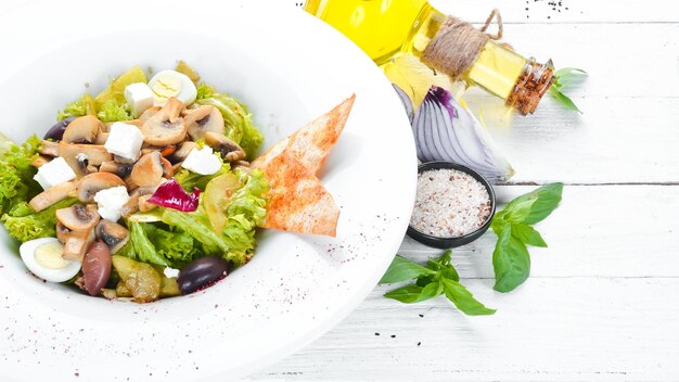 Foto insalata di verdure con funghi, olive e feta nel piatto vista dall'alto spazio libero per il testo stile rustico