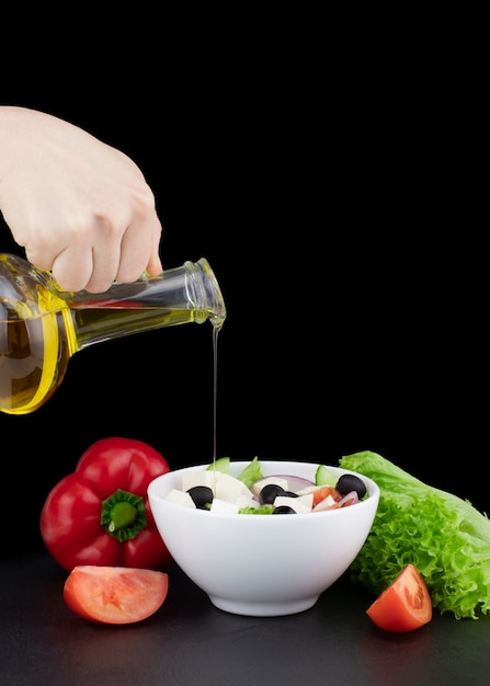 Овощной салат с оливковым маслом, льющимся из бутылки.