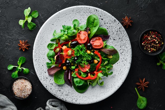 Vegetable salad with spinach tomatoes paprika and pumpkin seeds in a plate on a wooden background Top view Free space for your text Flat lay