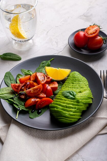 Vegetable salad with tomatoes, avocado and spinach in a grey plate. Healthy lifestyle concept