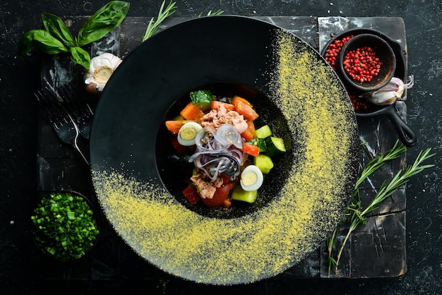 Овощной салат с тунцом в черной тарелке Вид сверху Деревенский стиль