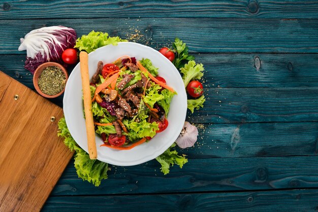 Vegetable salad with veal and mushrooms On a blue wooden background Top view Copy space for your text