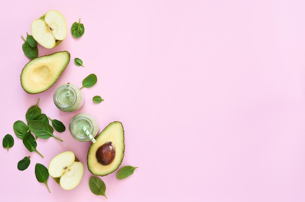 ピンクの背景にほうれん草とリンゴの野菜のスムージー。広告。デトックスドリンク。ケトダイエット。