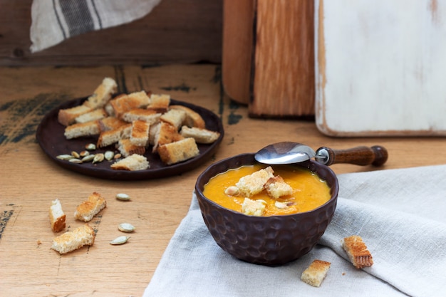 Zuppa di verdure con purea di zucca, carote e sedano, servita con crostini e semi di zucca. stile rustico.