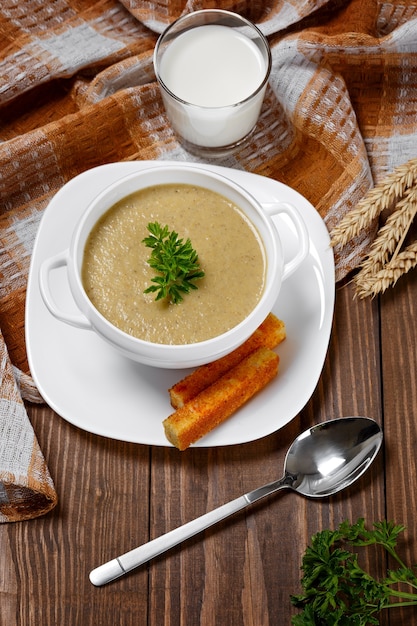 Vegetable soup with parsley and fried bread on a wooden table.