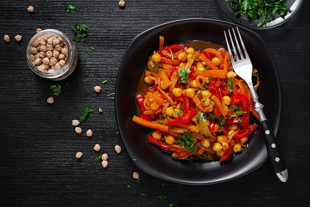 Stufato di verdure di ceci carota peperoni cipolle aglio e salsa di pomodoro con limone sul tavolo scuro cucina orientale vista dall'alto