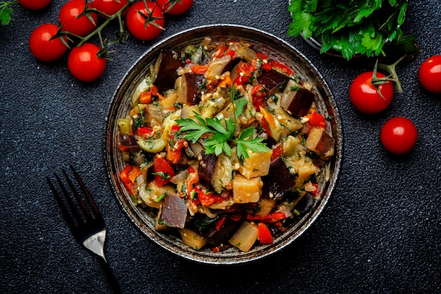 Vegetable stew saute or caponata Stewed eggplant with paprika tomatoes herbs and spices Black kitchen table background top view copy space