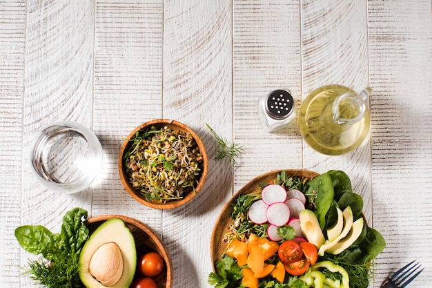 Vegetable summer salad with avocado seasonal vegetables spinach and microgreens on a wooden white background