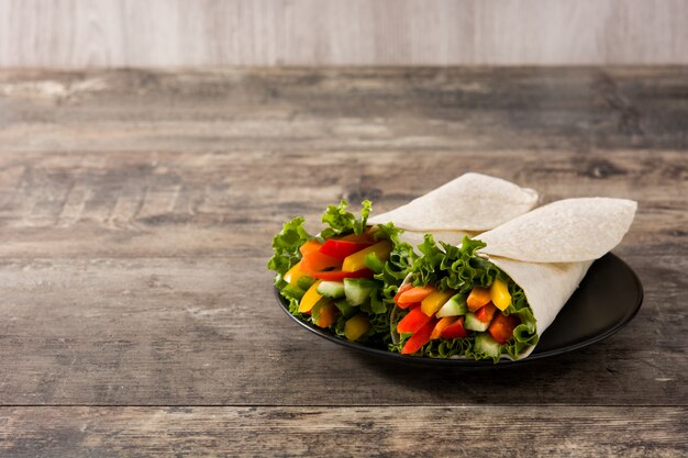 Vegetable tortilla wraps on wooden table copy space