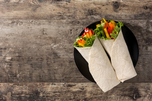 Vegetable tortilla wraps on wooden table top view copy space