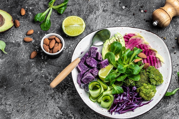 Vegetable vegan salad with sweet potatoes broccoli avocado purple cabbage cucumber watermelon radish and almonds Buddha Bowl Clean eating dieting food concept top view