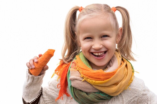 野菜は子どもたちの健康に。子供の小さな女の子はニンジンをかむし、白の野菜を楽しんでいます