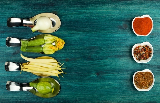 VEGETABLES ON BACKGROUND. FRESH VEGETABLES IN SPOONS ON A WOODEN SURFACE. COPY SPACE