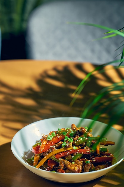野菜と牛肉の甘酸っぱいソースにシチャンペッパーを添えて。木の背景。中華料理