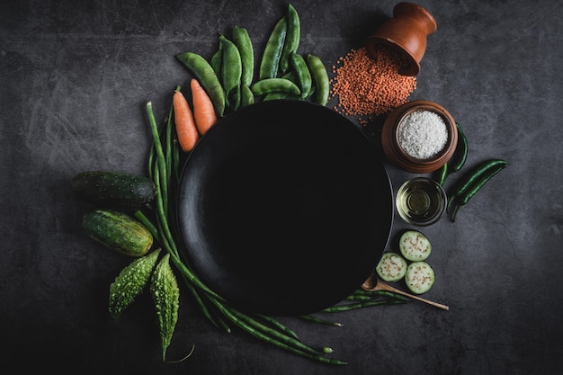 黒いプレートの真ん中の中のメッセージのためのスペースと黒いテーブルの上の野菜