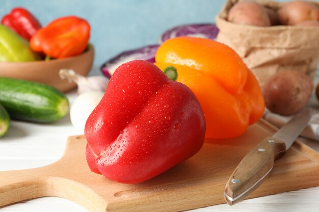 Vegetables, board and knife on white wooden close up