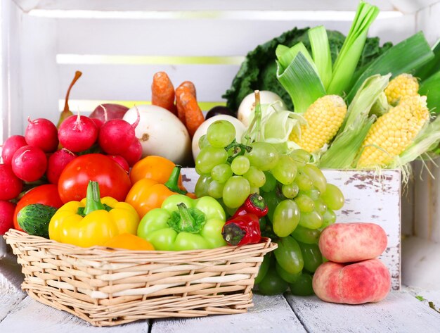 Vegetables in crate and in basket on white wooden box background