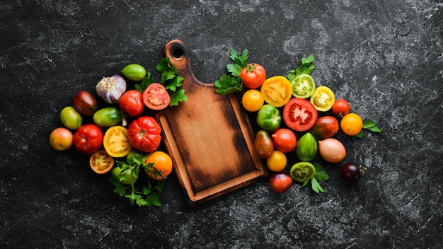 Vegetables Fresh colored tomatoes On a black stone background Top view Free space for your text