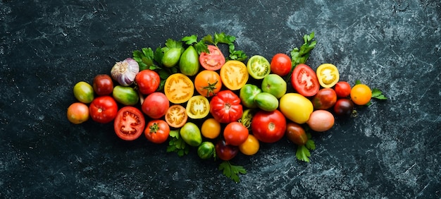 Vegetables Fresh colored tomatoes On a black stone background Top view Free space for your text