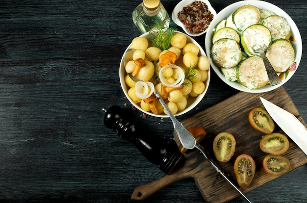 Vegetables . Fried zucchini sauce in a plate. Young boiled potatoes with dill in a bowl. Fried chanterelle mushrooms with golden onions in a frying pan. copyspace