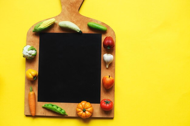 Verdure e frutta sul tagliere su sfondo giallo concetto di cucina sana