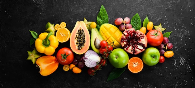 Vegetables and fruits healthy food Fruits and vegetables on black stone background Tropical fruits Top view Free space for your text