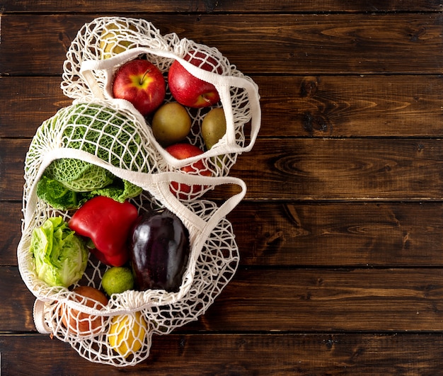 Vegetables and fruits in net bags on dark rustic background