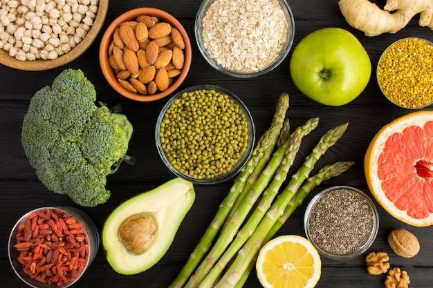 Vegetables, fruits, nuts and bee pollen on the black wooden background