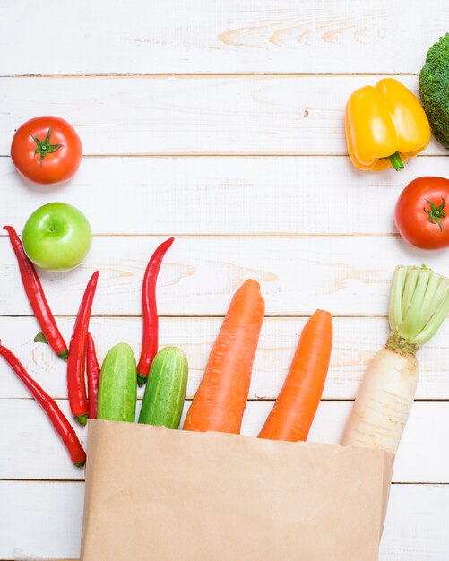 白い木製の背景に買い物袋の野菜