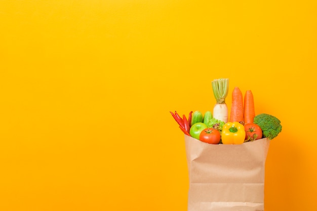 Овощи в продуктовой сумке на желтом фоне