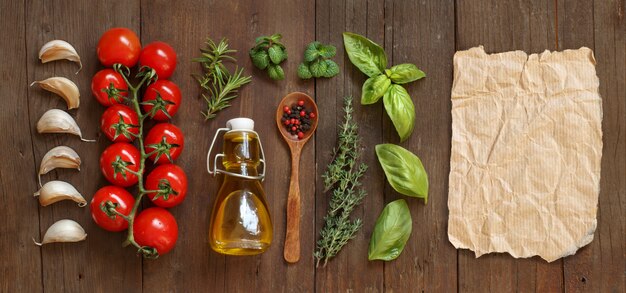 Vegetables, herbs and olive oil with craft paper on brown wooden table top view