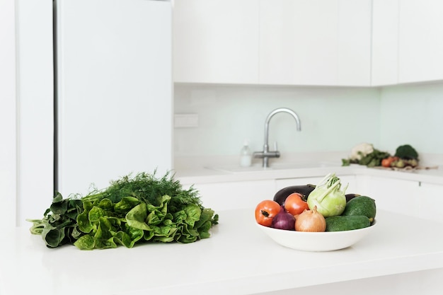 Vegetables and herbs for vegetarian meal on white kitchen table