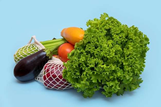 Vegetables lettuce celery zucchini eggplant in a shopping bag on a blue background