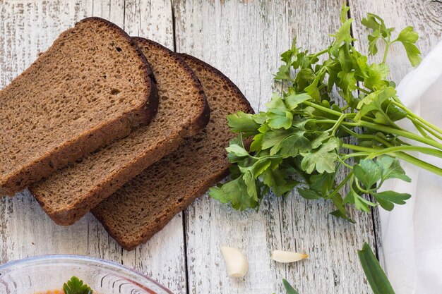 Vegetables and meat in red beetroot soup or borsch with sour cream. bread, green onion, parsley, garlic around the plate with metal spoon