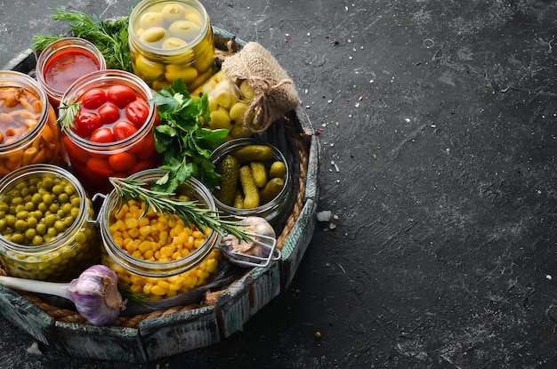 Vegetables and mushrooms in glass jars food stocks On a black background Top view