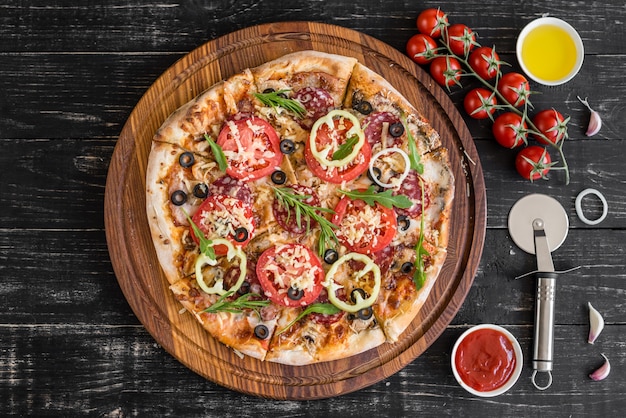 Vegetables, mushrooms and tomatoes pizza on a black wooden background. It can be used as a background