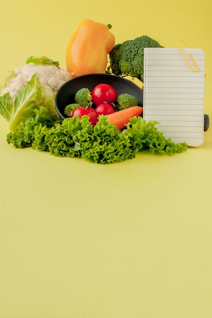 Овощи и тетрадь с copyspace на желтом цвете. Био Здоровая пища, органические овощи на желтом