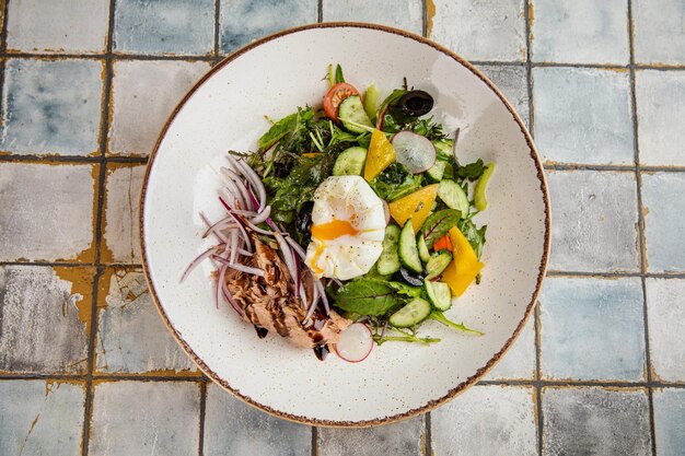 Vegetables salad and egg with soup plate of cold okroshka soup with kvass on a white plate